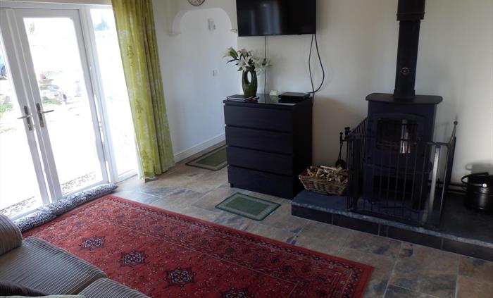 Lounge area showing the 43" tv, the multifuel fire, 3 seater sofa bed and patio door leading out to the patio and Jacuzzi garden area